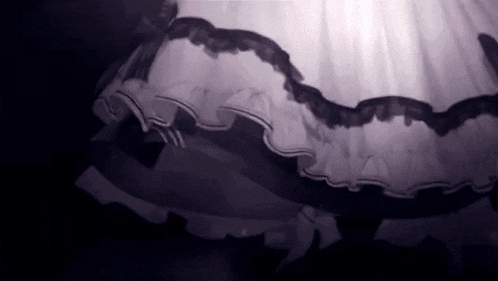 a black and white photo of a dress with ruffles and a bow on it .
