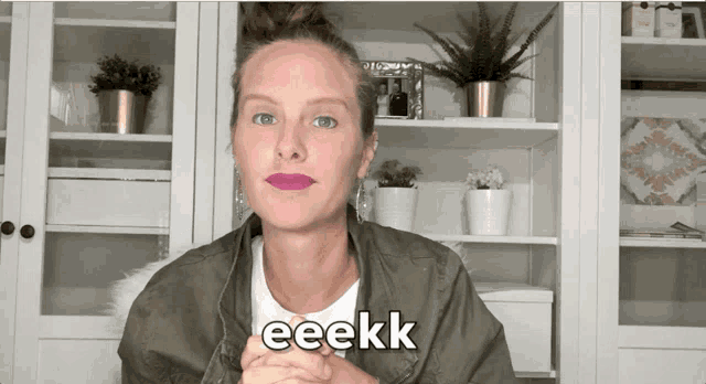 a woman in a green jacket says eeekk in front of a shelf