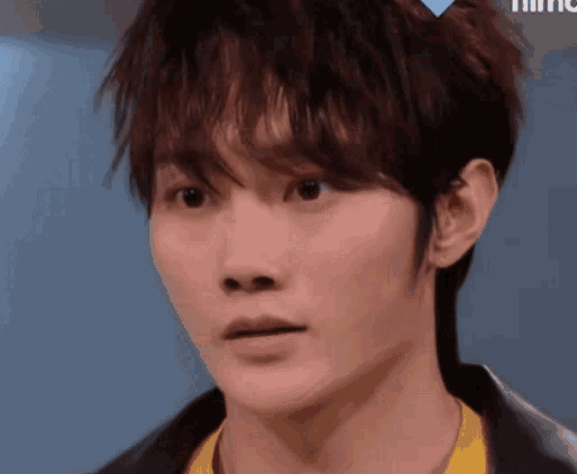 a close up of a young man wearing a yellow shirt and a black jacket .