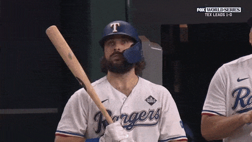 a man in a rangers jersey holds a bat