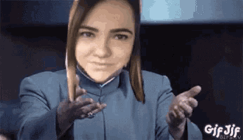 a woman in a blue jacket is giving a thumbs up and a thumbs down .