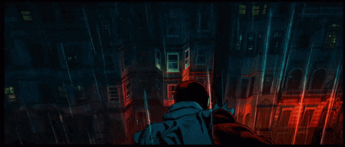 a man is standing in the rain in front of a building with a red light