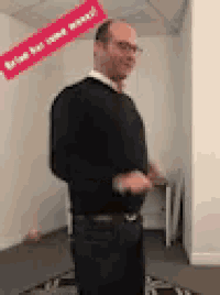 a man in a black sweater is standing in a room with a sign that says brian has won weekend .