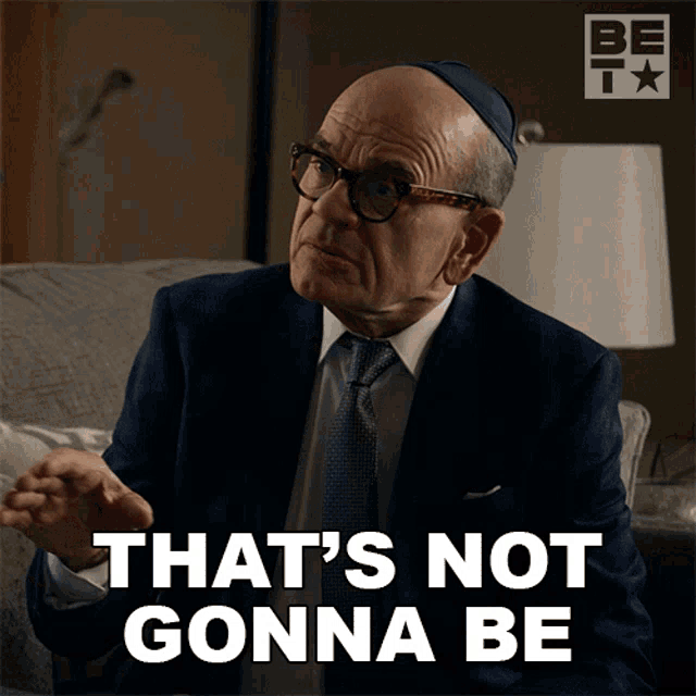 a man in a suit and tie is sitting on a couch and says that 's not gonna be