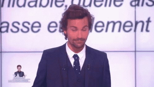 a man in a suit and tie is standing in front of a screen that says " journal "