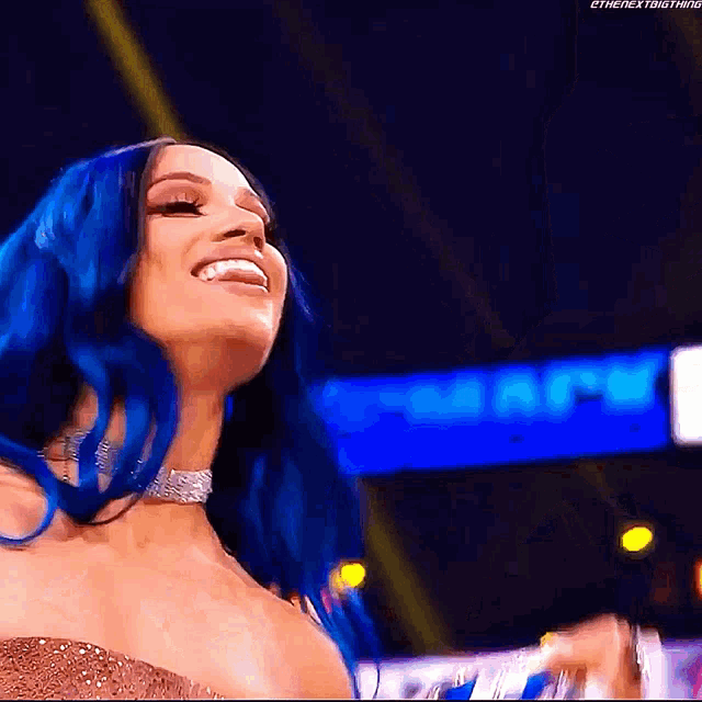 a woman with blue hair is smiling and wearing a gold dress .