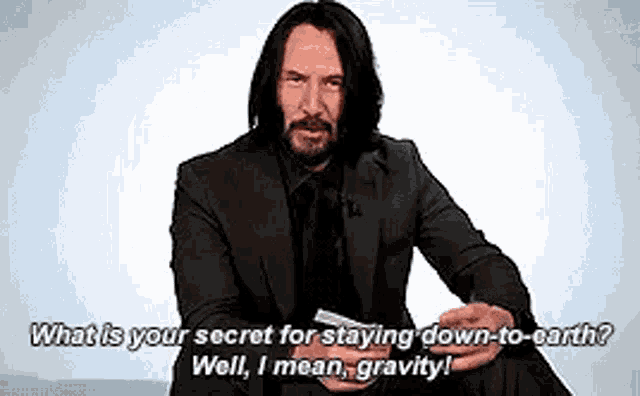 a man in a suit is sitting down and holding a piece of paper in his hand while talking .