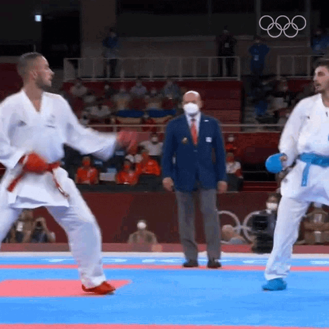 two men in white karate uniforms are fighting on a mat