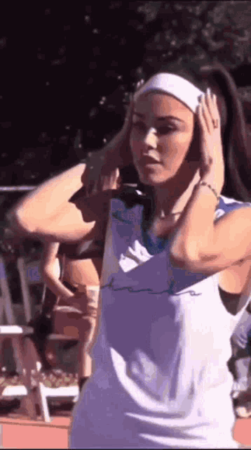 a woman wearing headphones and a headband is standing on a track .