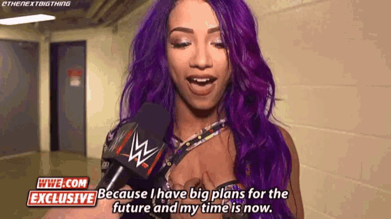 a woman with purple hair is talking into a microphone while wearing a wwe exclusive shirt .