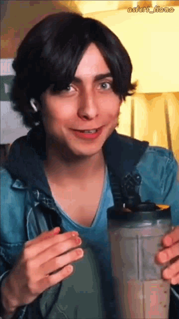a young man with braces on his teeth is holding a blender and smiling .