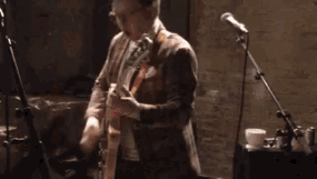 a man is singing into a microphone while playing a guitar .