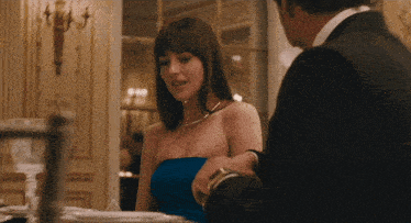 a woman in a strapless blue dress is sitting at a table with a man in a suit