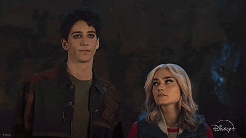 a man and a woman are standing next to each other with a disney logo behind them