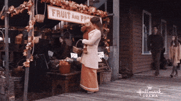 a woman holding a baby in front of a fruit and vegetable stand from hallmark drama