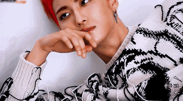 a man with red hair is wearing a black and white sweater and earring