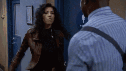 a woman in a leather jacket is standing next to a man in a striped shirt in front of a blue door .