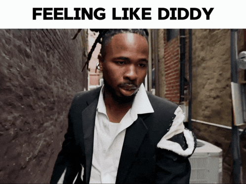 a man in a suit and white shirt is walking down an alley with the words feeling like diddy below him