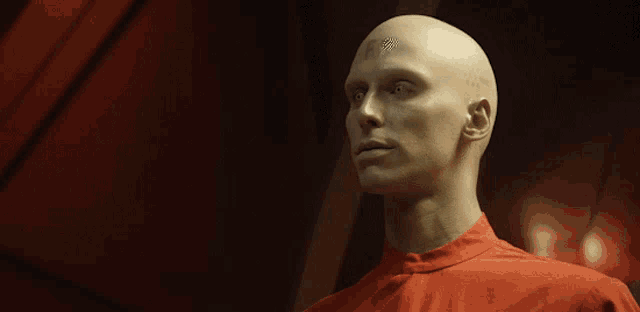 a bald man with a red shirt on looks down