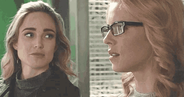 two women wearing glasses are looking at each other .