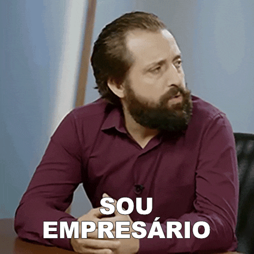 a man with a beard is sitting at a table with the words " sou empresario " written above him