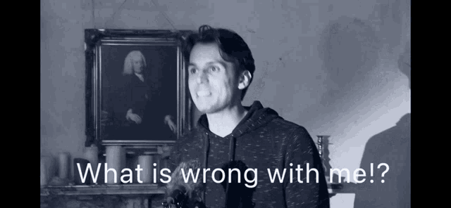a man stands in front of a painting with the words what is wrong with me written below him