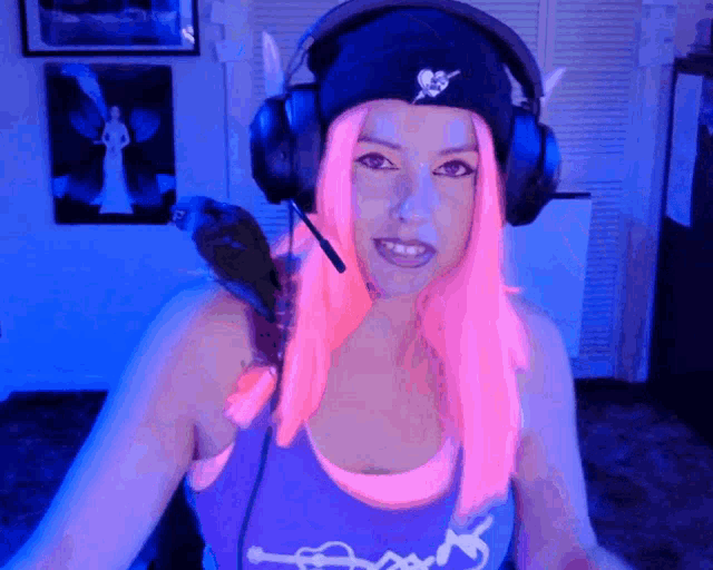 a woman with pink hair wearing headphones and a beanie with a skull on it