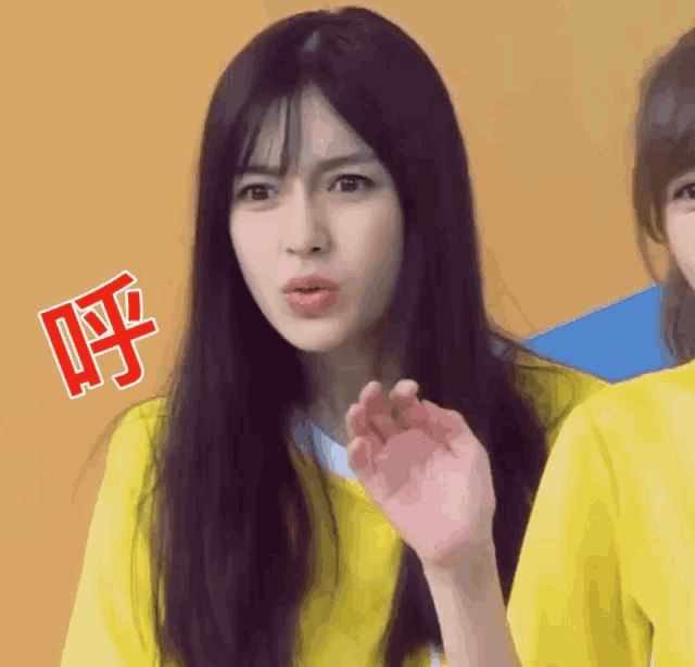 a girl with long black hair is wearing a yellow shirt with chinese writing on it