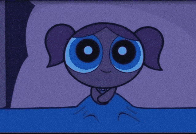 bubbles from the powerpuff girls is laying in a bed with a blue blanket .