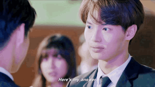a man in a suit says here 's my answer in front of a group of people