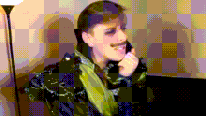 a man with a mustache is wearing a sequined jacket and talking on a cell phone