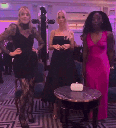 a woman in a pink dress stands next to two other women in black dresses