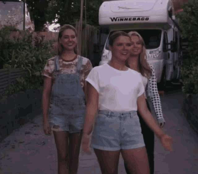 three women are walking in front of a winnebago rv