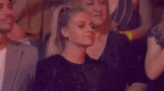 a woman in a black dress is standing in a crowd of people at a party .