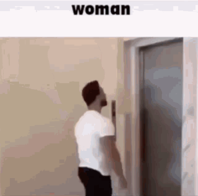 a man in a white shirt is standing in front of an elevator and looking up at it .