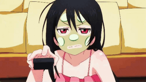 a girl with a green mask on her face is holding a remote control