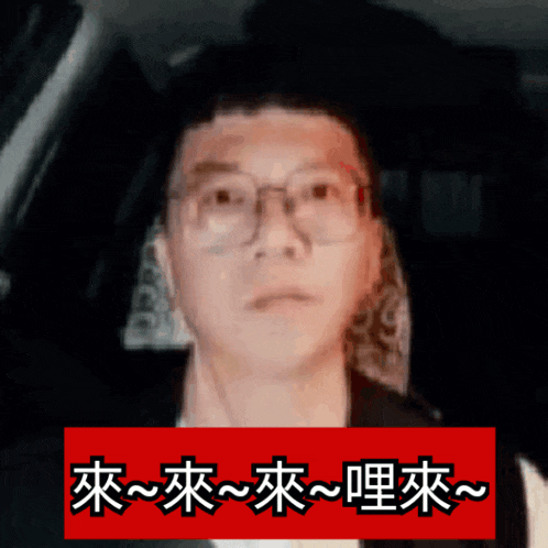 a man wearing glasses is behind a red sign with chinese writing on it