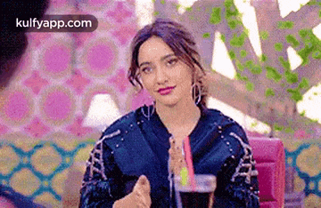 a woman is sitting at a table with a drink in her hand and a straw .