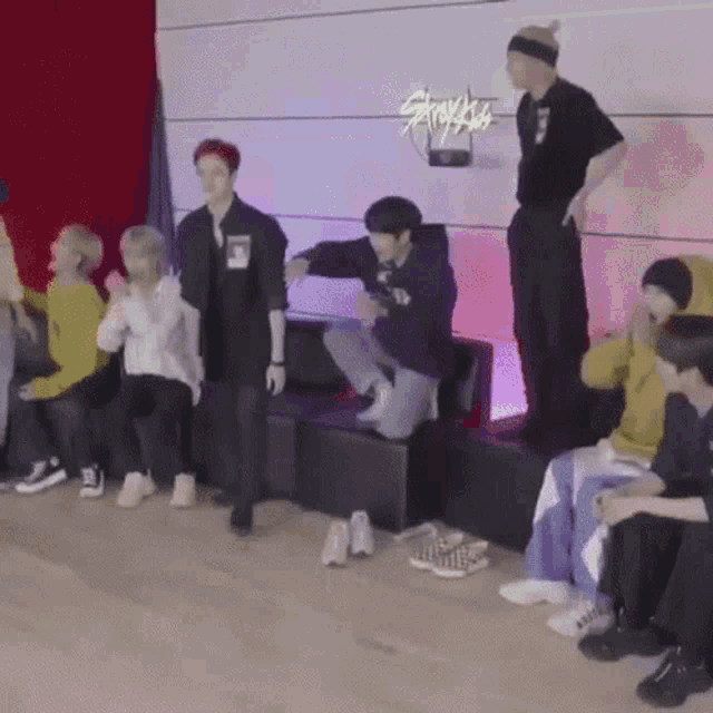 a group of people are standing in a room with a sign that says stray kids