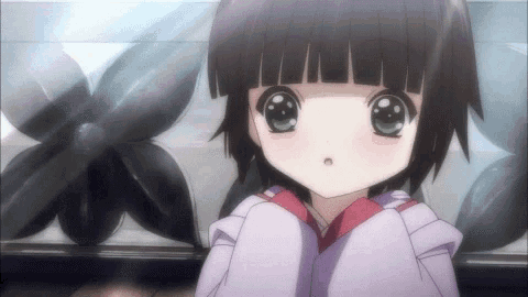 a little girl with black hair and green eyes is sitting in front of a flower