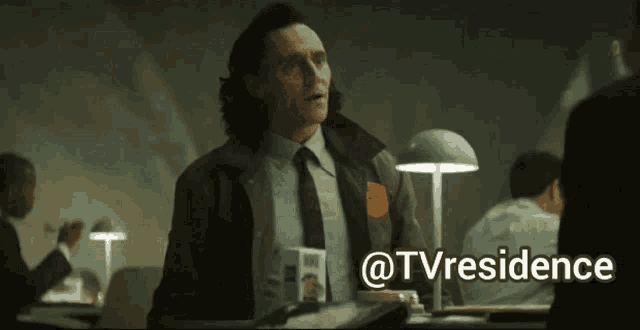 a man in a suit and tie is sitting at a desk in an office with the words @tvresidence above him