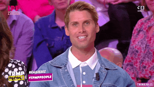 a man in a denim jacket is smiling in front of a crowd of people on a tv show called tmp people