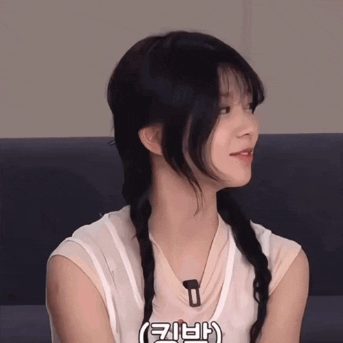 a woman with a braided hair style is wearing a white tank top and a necklace