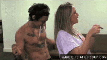 a shirtless man is smoking a cigarette while a woman watches .