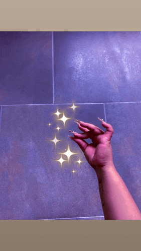 a woman 's hand with long nails is reaching up towards a purple tiled wall