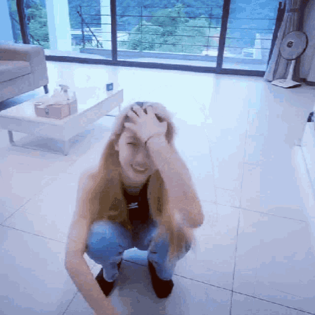 a woman kneeling down with her hand on her head in a living room