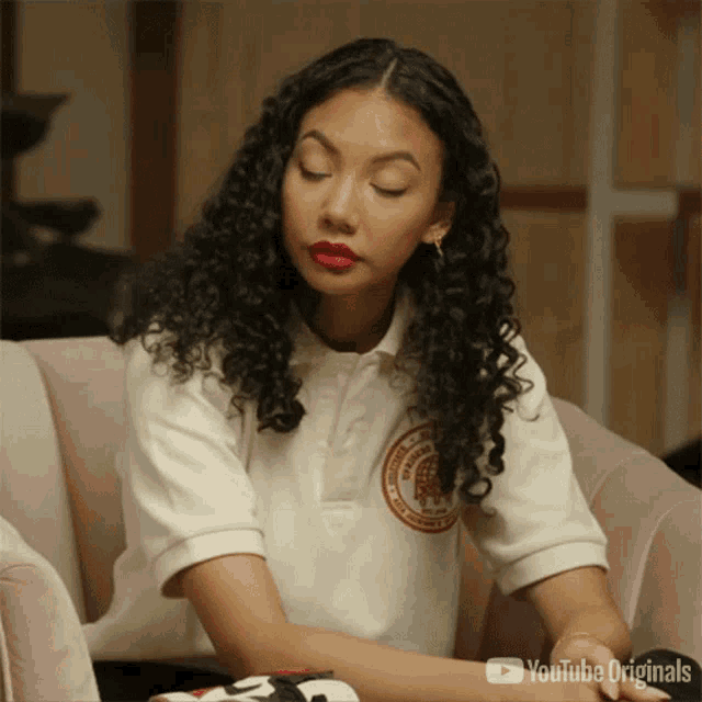 a woman with curly hair and red lipstick is sitting on a couch .