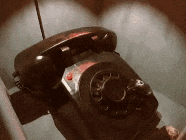 a black telephone with a red button on the top of it