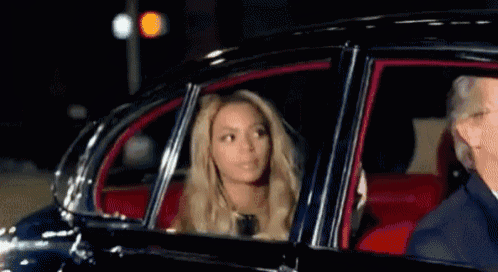 a woman is sitting in a car looking out of the window .
