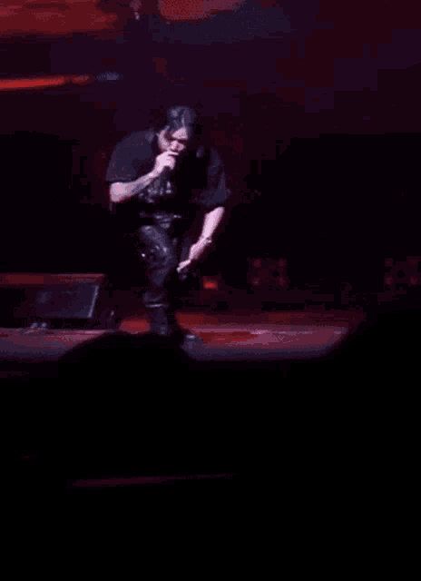 a man in a harley davidson shirt stands on a stage